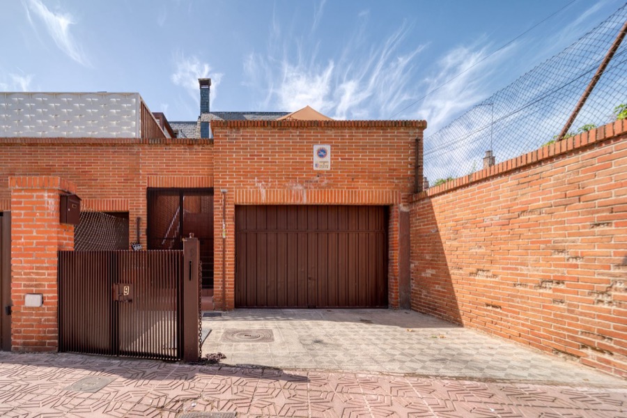 Portão de garagem e cancela pedonal em tom madeira escuro, numa fachada de tijolo