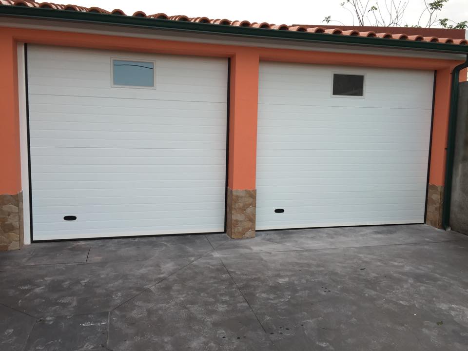Dois portões seccionados brancos instalados numa moradia